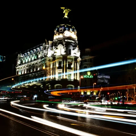 Edificio Metropolis iluminado de noche en la Gran Vía de Madrid, con estelas de luz de los coches