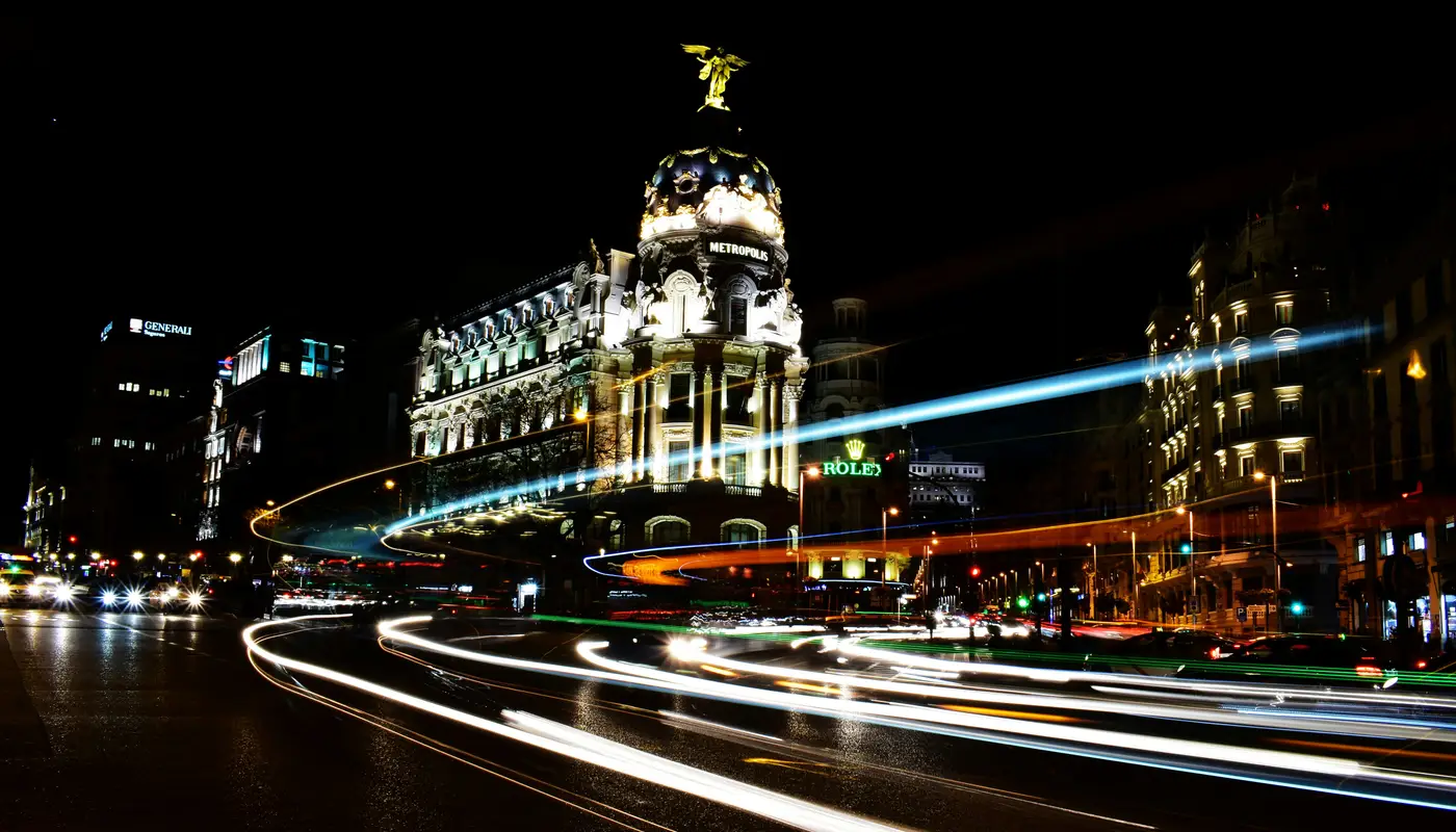 Edificio Metropolis iluminado de noche en la Gran Vía de Madrid, con estelas de luz de los coches