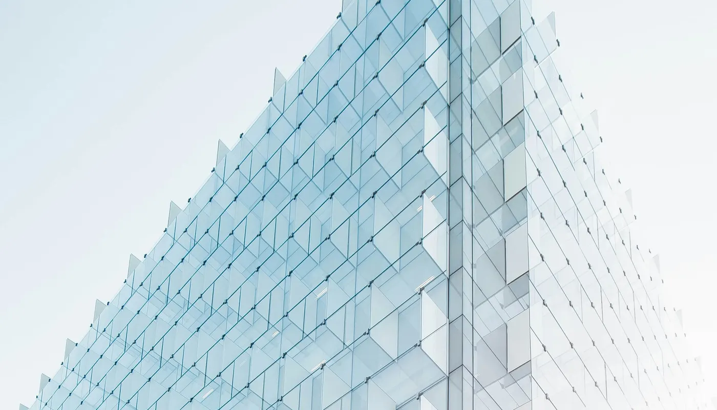 Fachada de un edificio de cristal moderno fotografiada en ángulo ascendente, con reflejos azulados